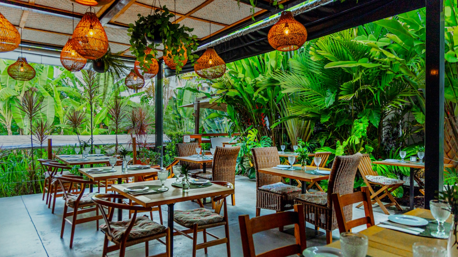 O jardim do Mundo Selvagem à noite, com luminárias de rattan acesas entre a vegetação tropical