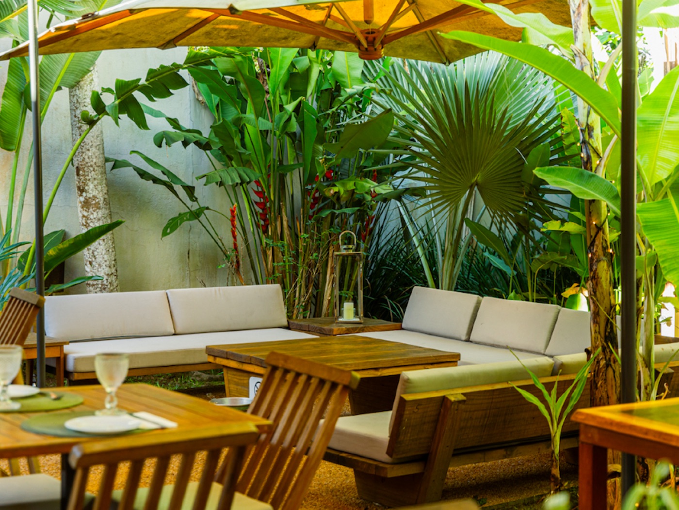 Lounge do jardim com sofás, guarda-sol e vegetação tropical exuberante